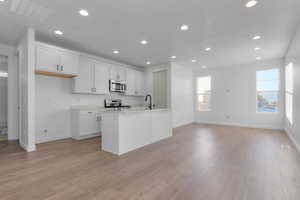 Kitchen featuring white cabinets, recessed lighting, light wood-style flooring, stainless steel appliances, and open floor plan