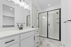 Bathroom with a shower stall, vanity, a walk in closet, and recessed lighting