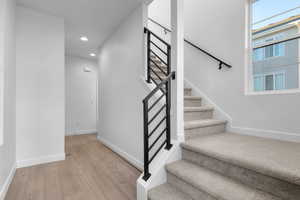 Stairs featuring wood finished floors and recessed lighting