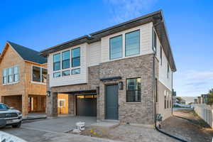 Contemporary house with brick siding, concrete driveway, and a garage