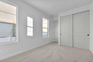 Unfurnished bedroom with light carpet and a closet