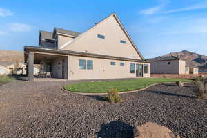 Rear view of property with a mountain view, a patio area, stucco siding, a yard, and a standing seam roof