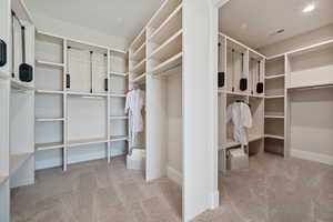 Walk in closet featuring light colored carpet