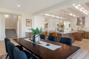 Dining room featuring light wood finished floors, stairs, beam ceiling, and recessed lighting