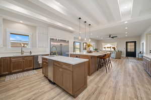 Kitchen featuring open floor plan, recessed lighting, brown cabinetry, decorative light fixtures, and beamed ceiling