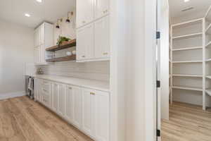 Kitchen with white cabinets, recessed lighting, light wood-style flooring, open shelves, and decorative backsplash