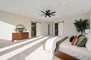 Bedroom with a barn door, carpet floors, recessed lighting, ensuite bathroom, and ceiling fan