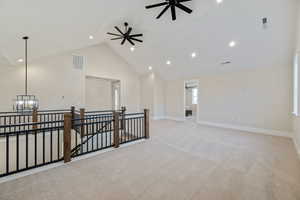 Empty room with high vaulted ceiling, light colored carpet, a chandelier, a ceiling fan, and recessed lighting