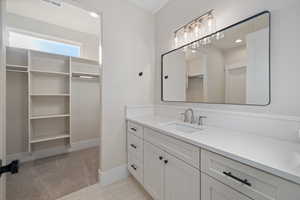 Bathroom featuring a spacious closet, vanity, and recessed lighting