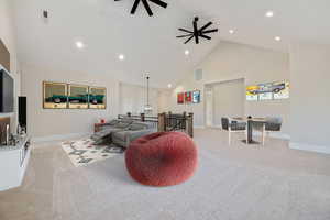 Living room with high vaulted ceiling, light carpet, and recessed lighting