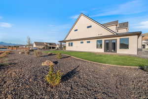 Rear view of house with stucco siding, a yard, a patio area, and french doors