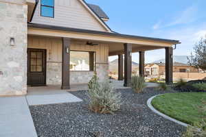 Doorway to property with board and batten siding, covered porch, ceiling fan, and a mountain view