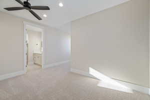 Unfurnished bedroom with light colored carpet, recessed lighting, ensuite bath, and ceiling fan