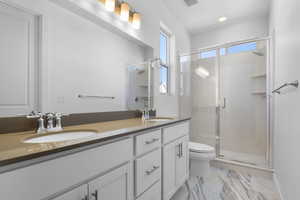 Full bath featuring a shower stall and double vanity