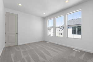 Spare room featuring light carpet, plenty of natural light, and recessed lighting