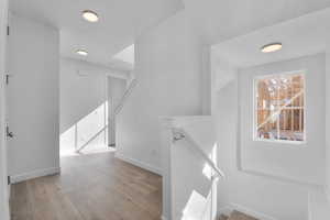 Hall with an upstairs landing and light wood-style floors