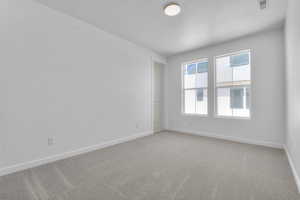 Carpeted empty room with a textured ceiling and baseboards