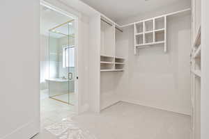 Walk in closet featuring light tile patterned flooring and light colored carpet