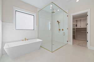 Full bathroom featuring a shower stall, a freestanding tub, a walk in closet, and recessed lighting
