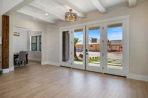 Doorway featuring wood finished floors, a chandelier, beamed ceiling, and french doors