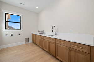Laundry area featuring electric dryer hookup, light wood-style floors, recessed lighting, washer hookup, and cabinet space