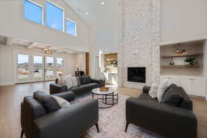 Living room with healthy amount of natural light, light wood-style floors, high vaulted ceiling, a fireplace, and recessed lighting