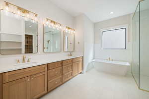 Full bathroom featuring a soaking tub, double vanity, a shower stall, a spacious closet, and recessed lighting