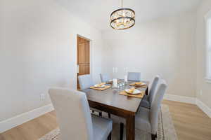 Dining area with light wood-type flooring and a chandelier