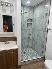 Bathroom with a stall shower, vanity, and wood finished floors
