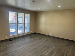 Spare room with a textured ceiling, dark wood finished floors, and recessed lighting