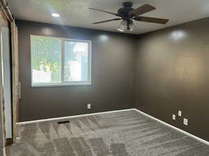 Carpeted empty room featuring a textured ceiling, a ceiling fan, and recessed lighting