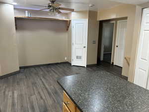 Empty room featuring dark wood-style flooring, a ceiling fan, and a textured ceiling