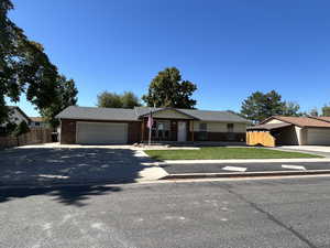 Single story home featuring driveway, a garage, and brick siding