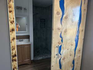Full bath with a shower stall, vanity, and wood finished floors