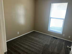 Spare room with baseboards and dark carpet