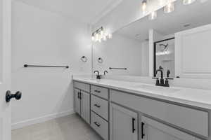 Bathroom featuring double vanity, a stall shower, and light tile patterned flooring