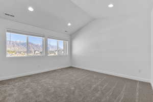 Empty room featuring lofted ceiling, light carpet, a mountain view, and recessed lighting