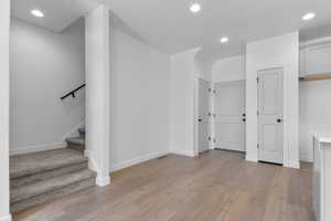 Below grade area with recessed lighting, light wood-style flooring, and stairway