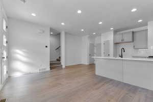 Unfurnished living room featuring stairway, recessed lighting, light wood finished floors, and a textured ceiling