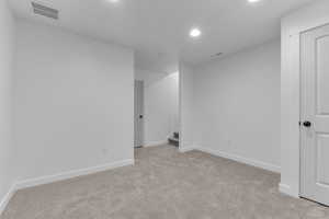 Unfurnished room with stairway, light colored carpet, and recessed lighting