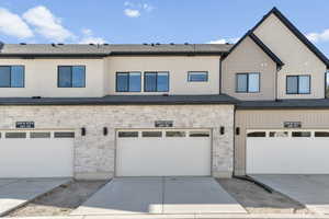 Rear view of property featuring stone siding, concrete driveway, and a garage