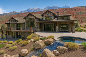 Back of house featuring stone siding, a patio area, an outdoor pool, and a mountain view