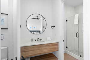 Bathroom with a shower stall, vanity, a ceiling fan, and light wood-style floors