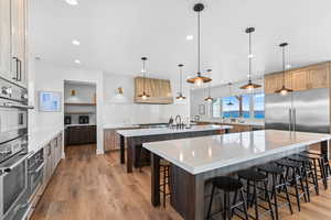 Kitchen with a breakfast bar, light stone counters, pendant lighting, appliances with stainless steel finishes, and backsplash