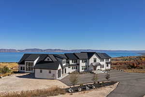 Modern farmhouse style home featuring driveway, a garage, a water and mountain view, a metal roof, and board and batten siding