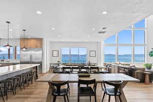 Dining space featuring light wood-type flooring, a water and mountain view, and recessed lighting