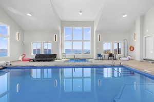 Indoor pool featuring a sunroom and a water view