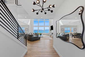 Living area with stairway, light wood-style floors, a high ceiling, recessed lighting, and a chandelier