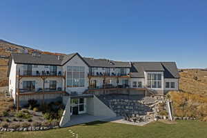 Rear view of house with a patio, a lawn, a balcony, and roof with shingles