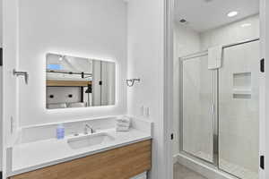 Ensuite bathroom with a shower stall, vanity, and recessed lighting